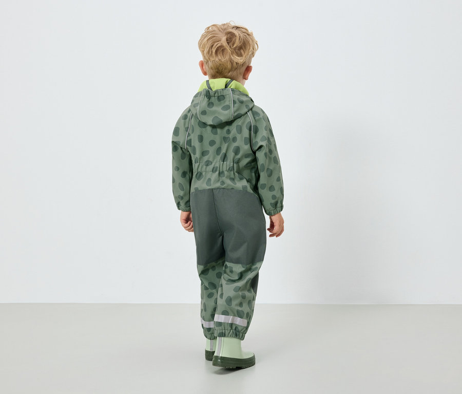 Garçon portant une combinaison verte à capuche, dos à la caméra.