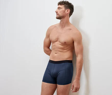 Un homme debout, les mains derrière le dos, portant un 2 Boxers de sport bleus.