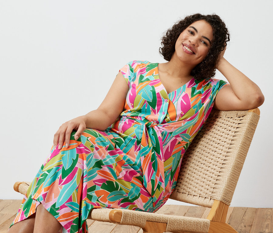 Une femme est assise sur une chaise et porte une robe en jersey avec nœud.