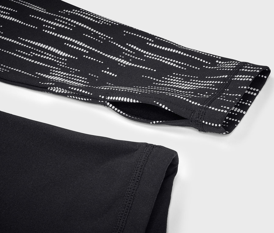 Détail d'un haut de sport noir à manches longues avec un motif géométrique blanc sur la manche.