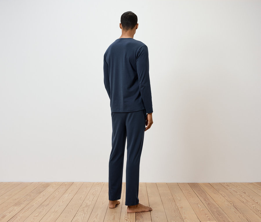 Un homme, dos à la caméra, porte un pyjama bleu marine.