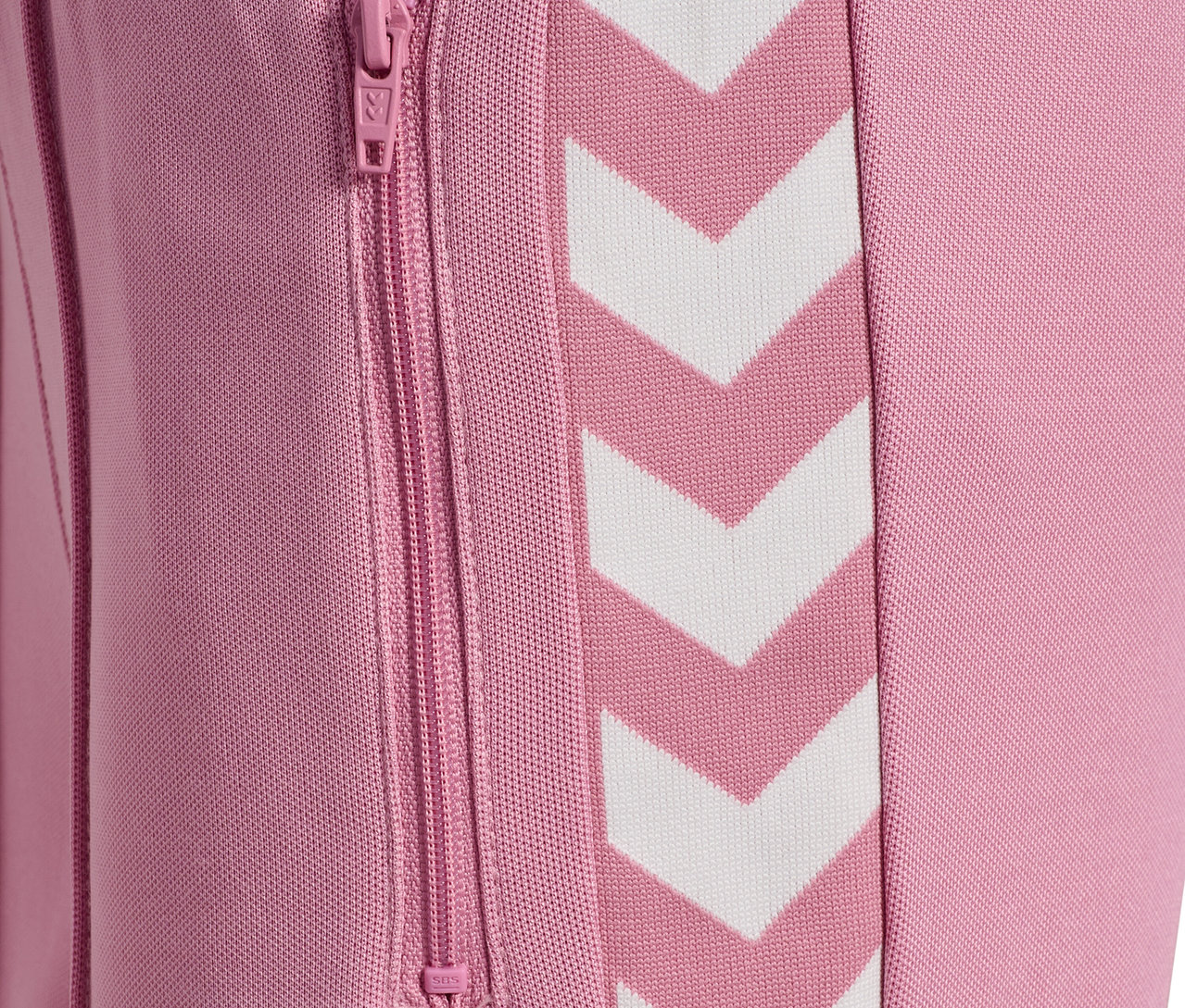 Détail d'un pantalon HUMMEL HMLJR Archive Wideleg Poly rose avec des chevrons blancs et une poche zippée.