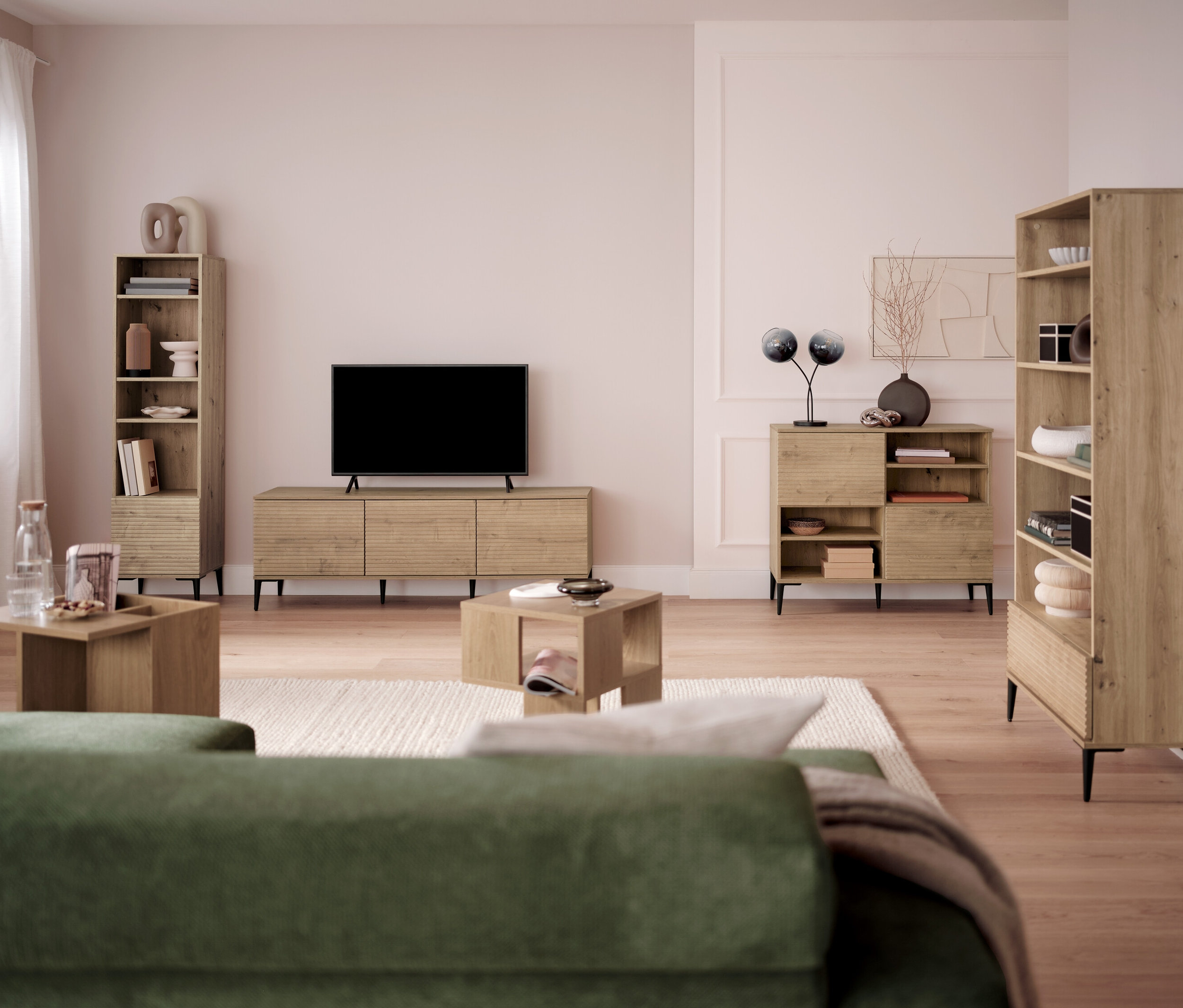 Salon avec téléviseur, bibliothèques et tables basses.