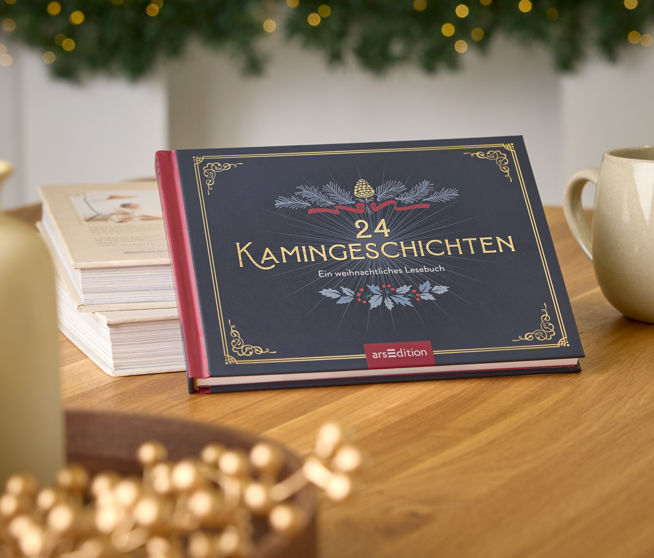 Livre "24 Kamingeschichten" sur une table en bois à côté d'une tasse et d'un vase, avec un arbre de Noël en arrière-plan.
