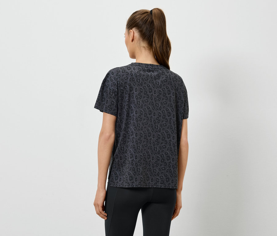 Femme portant un t-shirt foncé à motifs et des leggings, vue de dos.