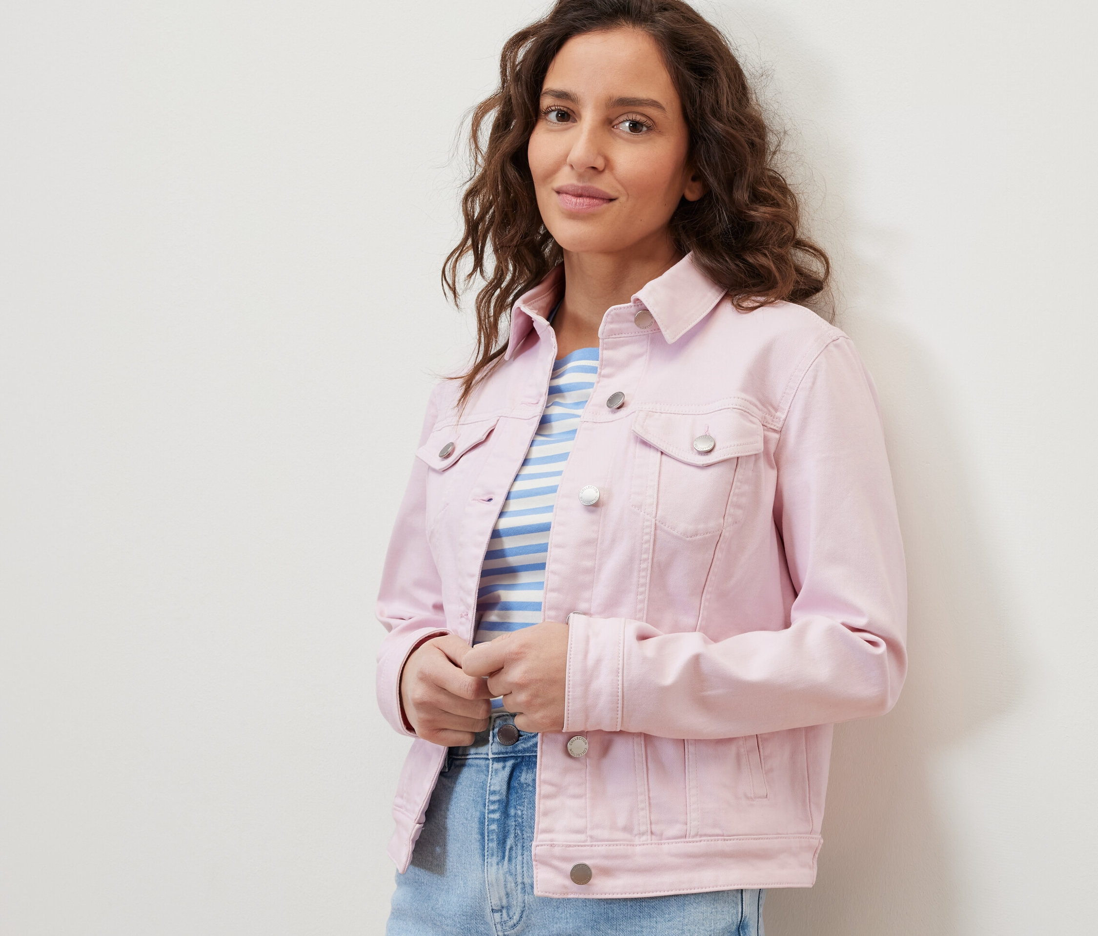 Une femme porte une veste en jean et un t-shirt rayé.