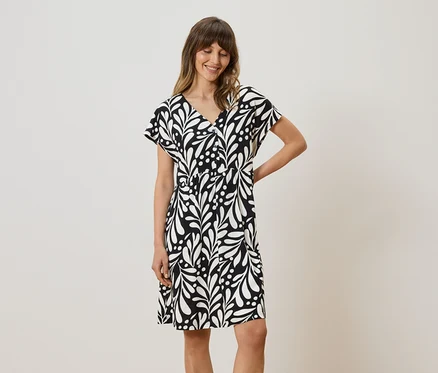 Femme portant une robe noire et blanche à motifs de feuilles.