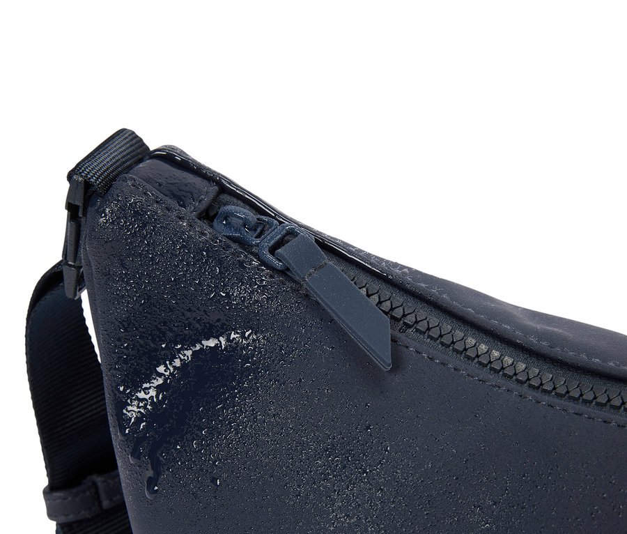 Gros plan d'un sac banane bleu marine avec fermeture éclair et gouttes d'eau.