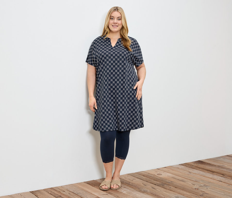Femme portant une robe à motifs et un legging 3/4 bleu marine avec bordure en dentelle.