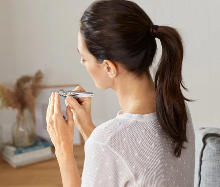 Femme regardant ses ongles avec une loupe à ongles.