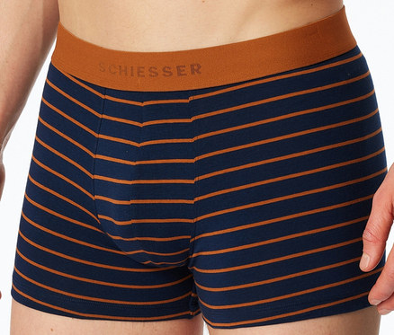 Gros plan sur une personne portant un boxer SCHIESSER rayé bleu marine et orange avec une ceinture orange.