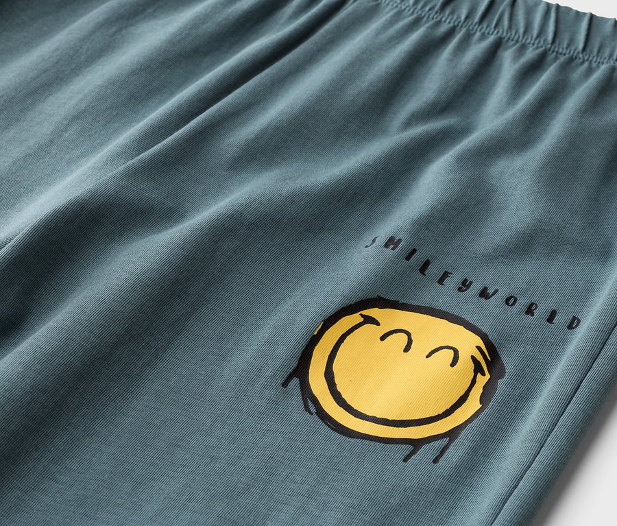 Gros plan d'un pantalon pétrole avec une taille élastique et un imprimé jaune Smileyworld.
