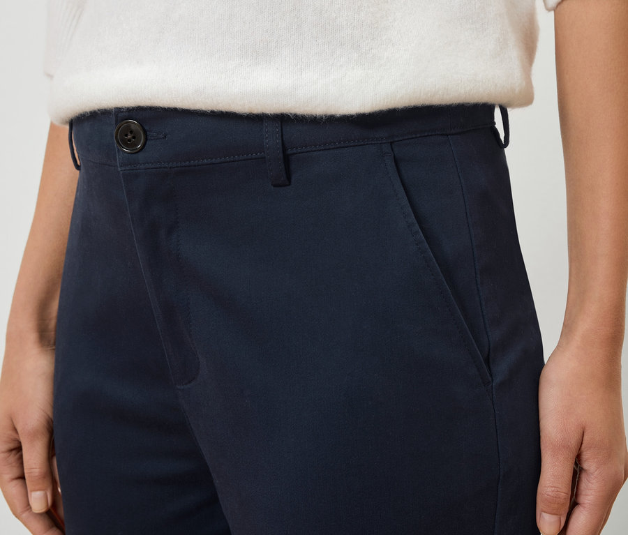 Gros plan d'une personne portant un pantalon bleu marine et un pull blanc.