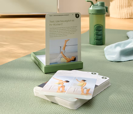 Sur un tapis de yoga vert se trouvent des cartes d'exercices, une bouteille d'eau verte et une boîte verte.