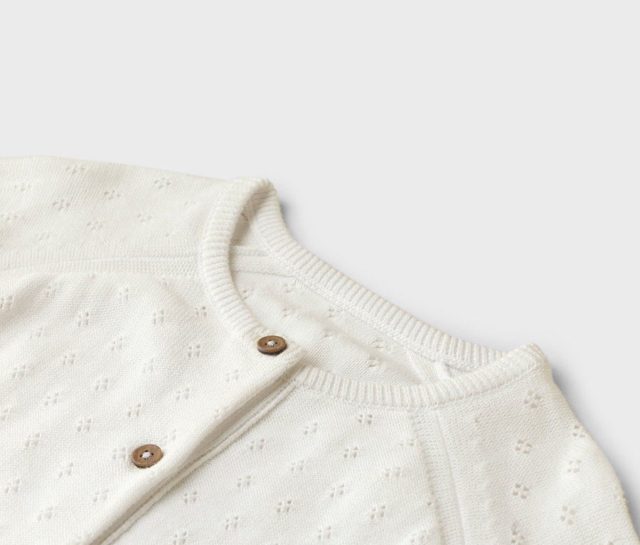 Gros plan sur un cardigan blanc avec deux boutons.