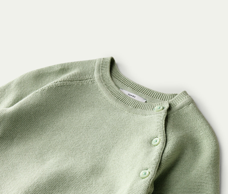 Gros plan sur un cardigan en tricot vert clair avec des boutons et un col rond.