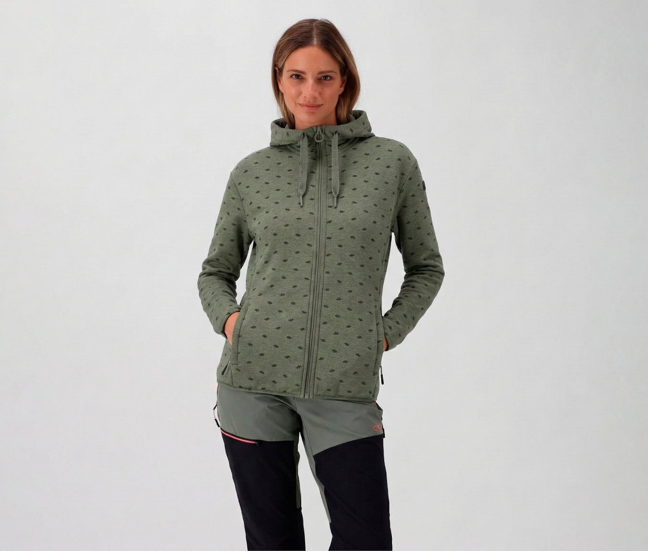 Une femme à capuche porte une veste polaire CMP pour femme avec capuche, avocat, et a les mains dans ses poches.