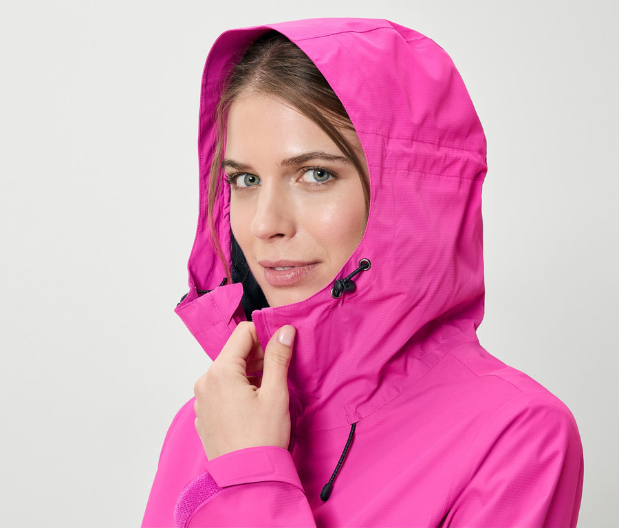 Femme fermant une veste de pluie rose.
