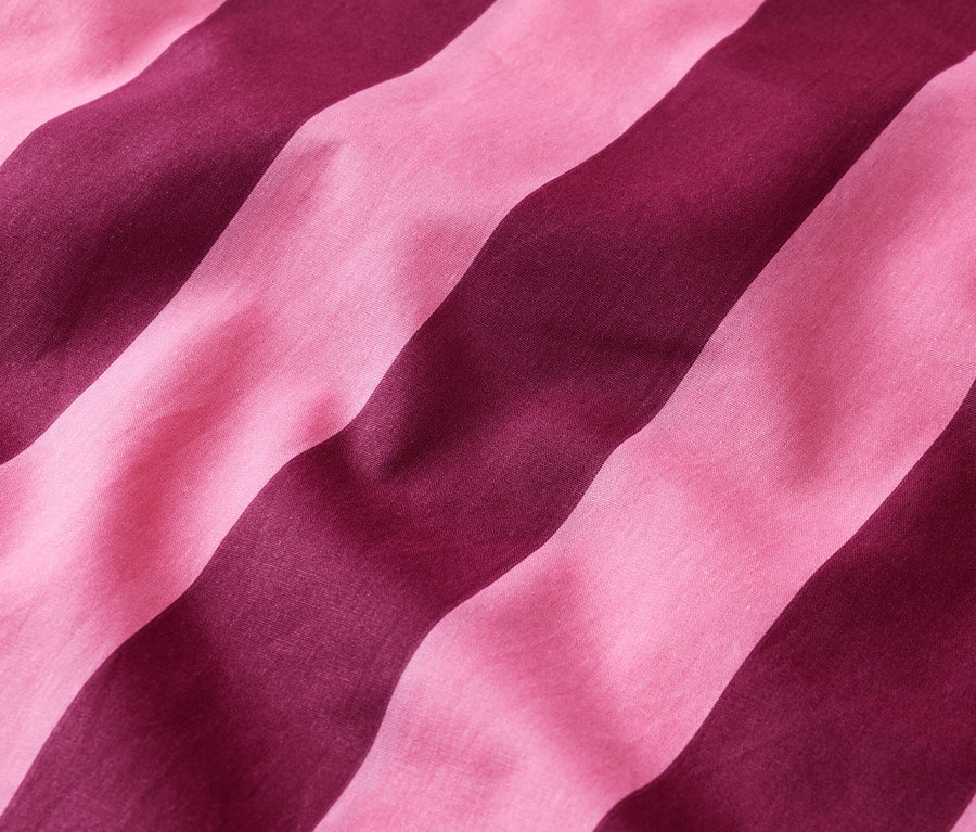 Gros plan de bandes de tissu rayées roses et bordeaux disposées en diagonale.