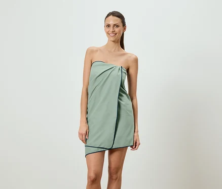 Femme portant une robe de serviette vert clair avec une bordure bleu marine.