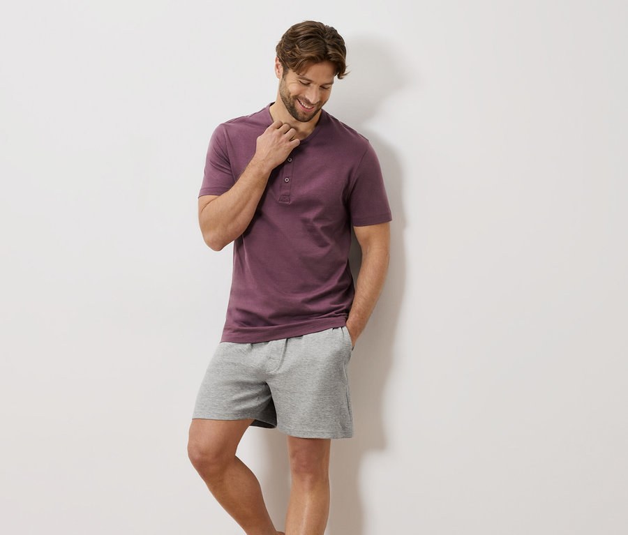 Homme portant un t-shirt bordeaux à boutons et un short gris.