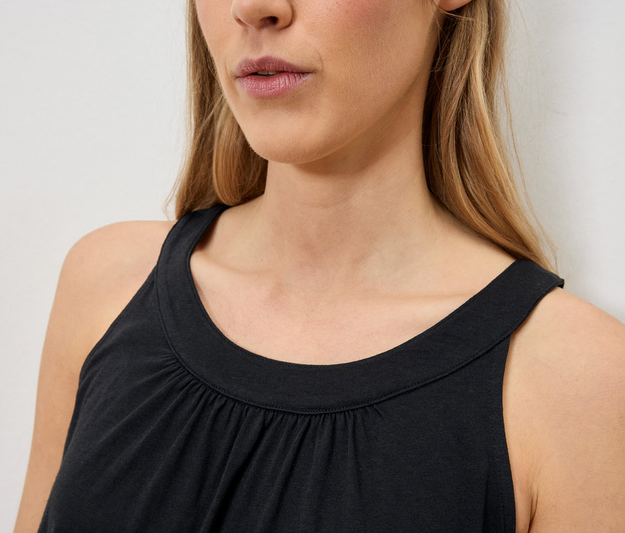 Gros plan d'une femme aux cheveux blonds portant un débardeur noir sans manches.