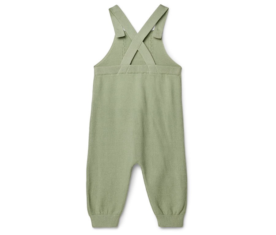 Une salopette en tricot vert clair unique posée à plat sur un fond blanc.