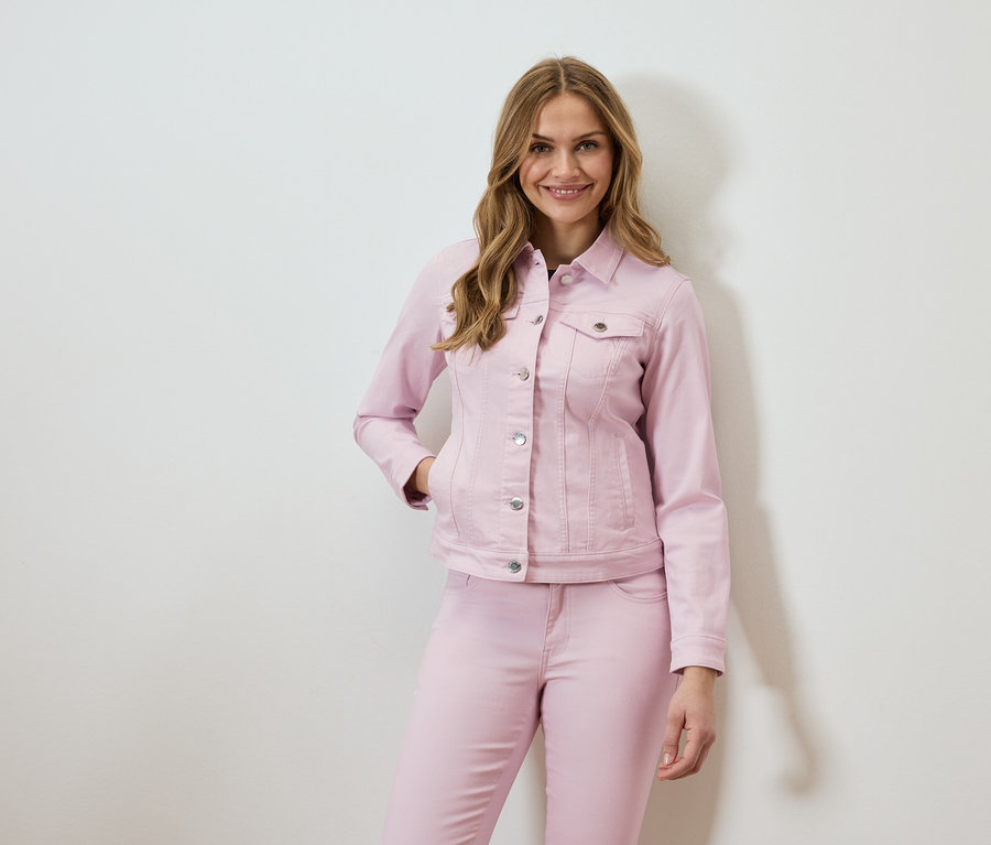 Une femme porte une veste en jean rose et un jean assorti.