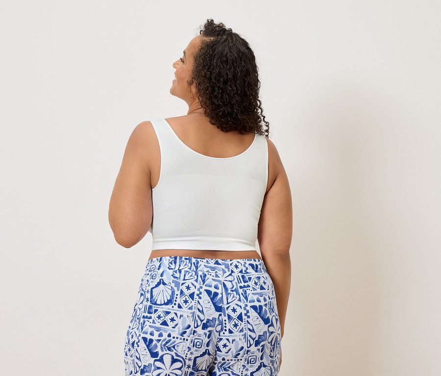 Femme vue de dos portant un crop top blanc et un pantalon à motifs bleu et blanc.