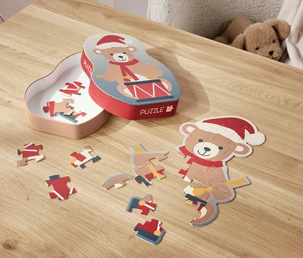 Un puzzle d'ours avec un bonnet de Noël est étalé sur une table, à côté de sa boîte.