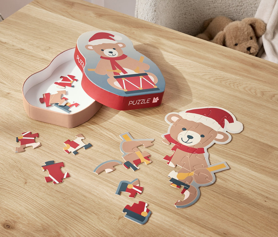 Un puzzle d'ours avec un bonnet de Noël est étalé sur une table, à côté de sa boîte.