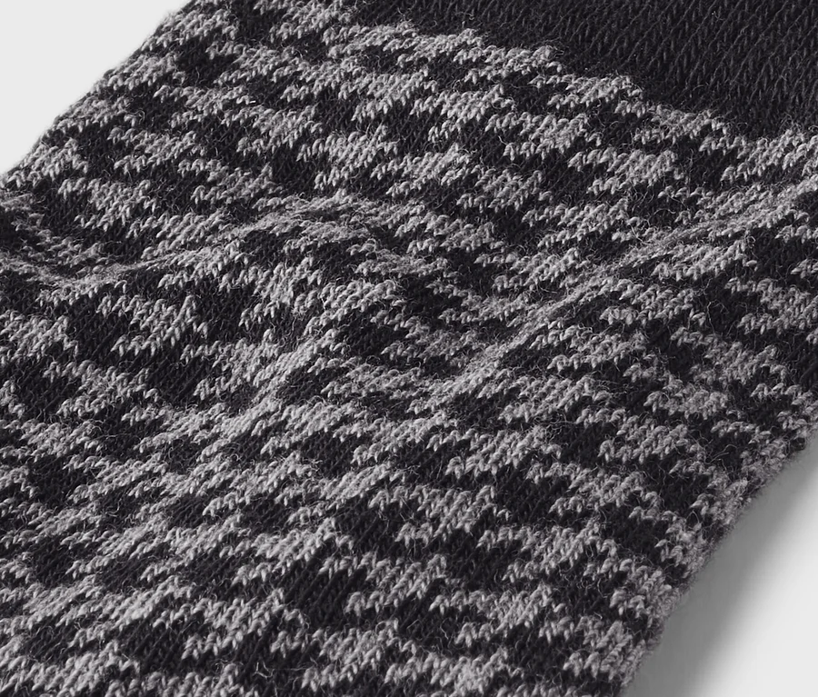 Gros plan d'un tissu tricoté noir et gris clair avec un motif moucheté. Une bande noire unie est visible en haut.