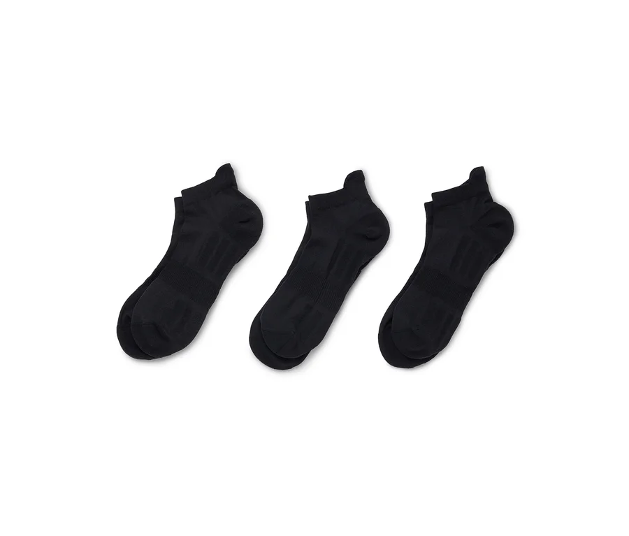 Trois chaussettes de cheville noires sont disposées en diagonale sur un fond blanc.