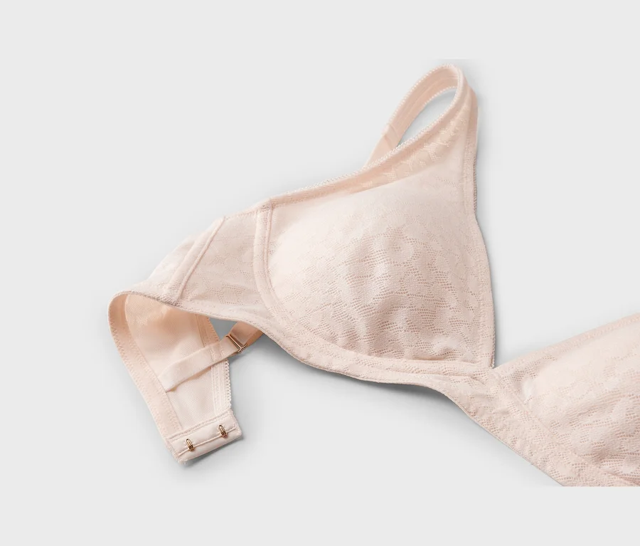 Soutien-gorge rose pâle à motif discret, avec un bonnet, une bretelle et l'agrafe visible.
