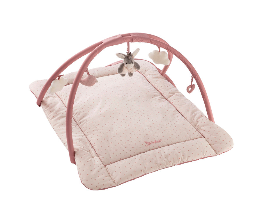 Tapis d'éveil rose pour bébé avec arche d'activités. Le tapis rose clair a de petits pois roses et une bordure rose foncé. De l'arche rose pendent un âne gris, deux nuages blancs, une baleine rose et un cœur rose.