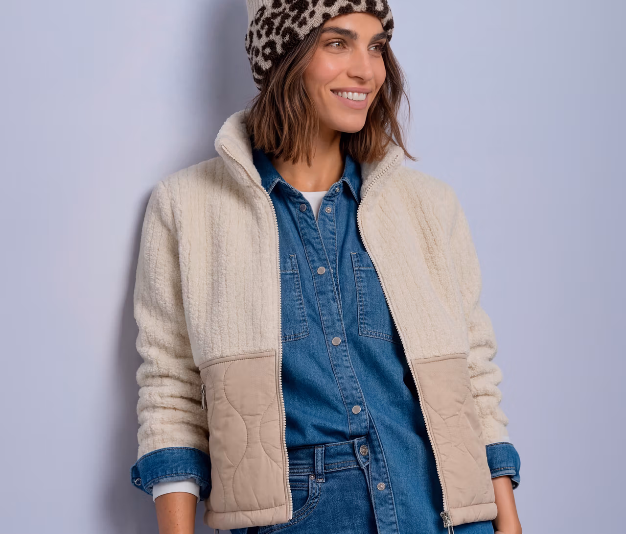 Femme souriante portant un bonnet léopard et une veste de mi-saison Street One crème avec empiècements matelassés beiges, sur une chemise en jean.