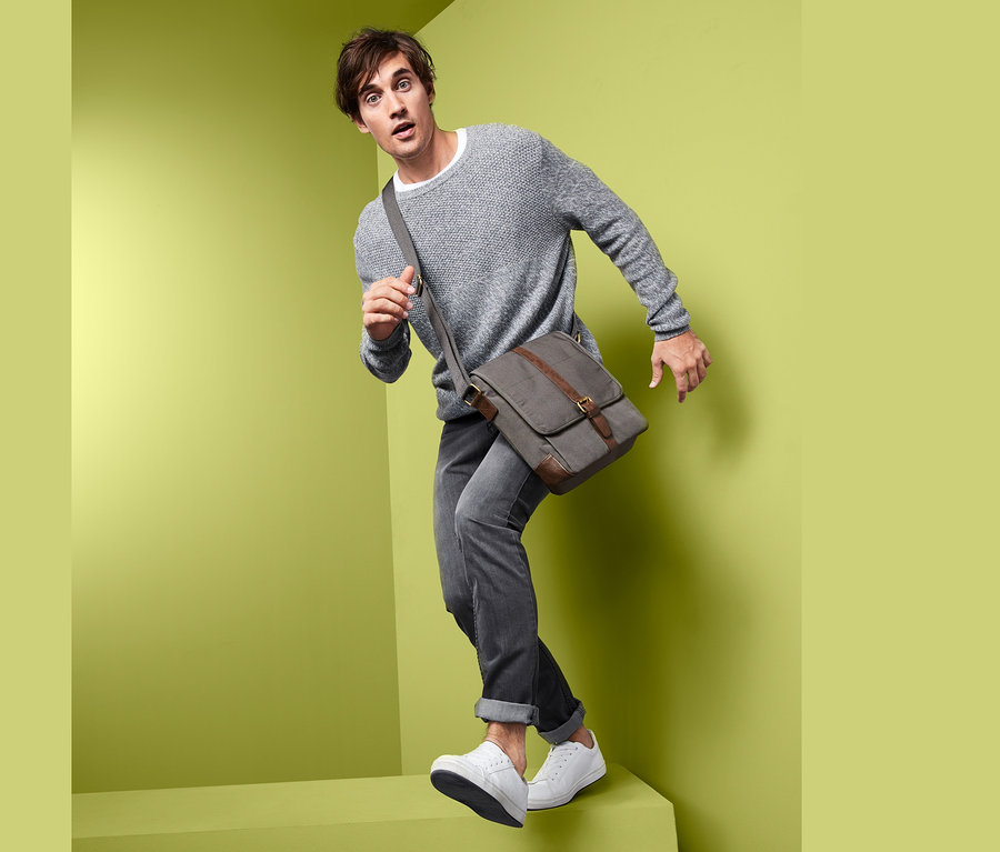 Un homme pose avec un sac à porter en travers.