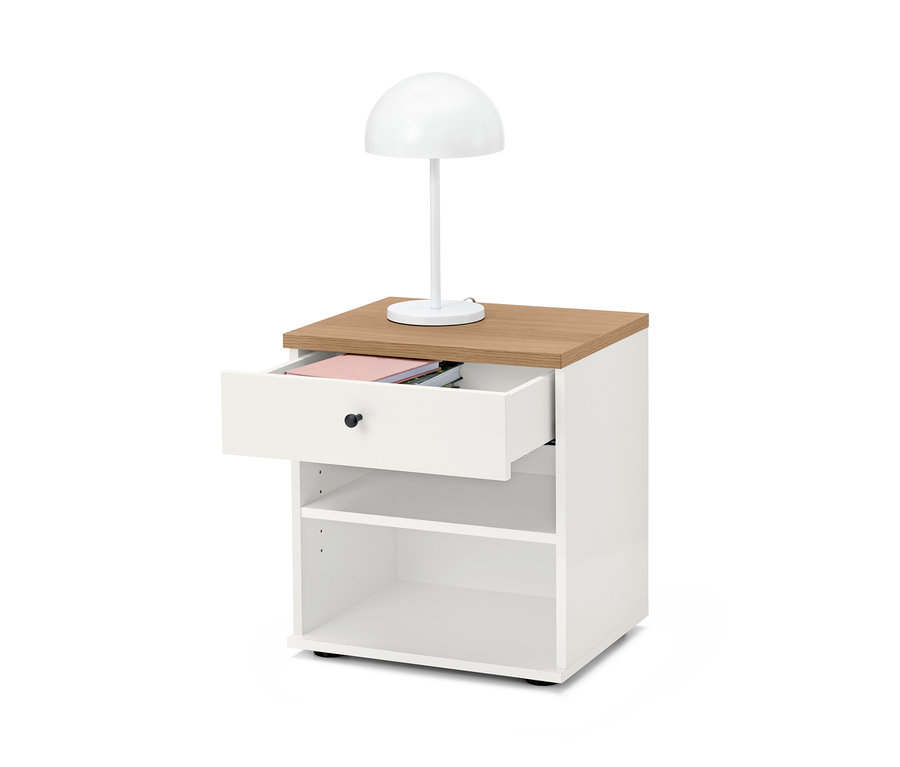 Table de chevet blanche »Bekeson« avec plateau marron et tiroir ouvert. Une lampe blanche est posée sur la table.