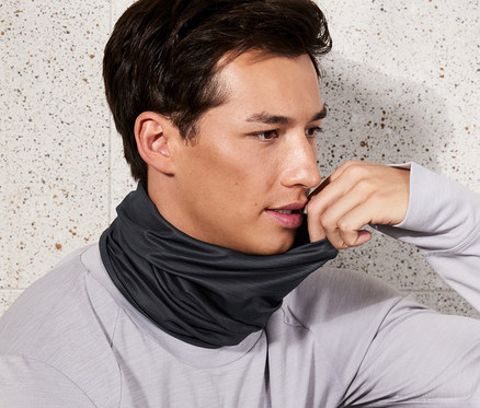 Un homme est assis et porte un foulard multifonction anthracite.