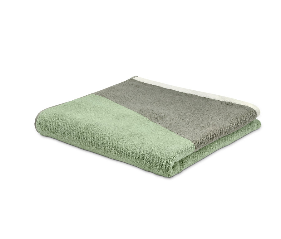 Une serviette de bain verte en jacquard est pliée sur un fond blanc.