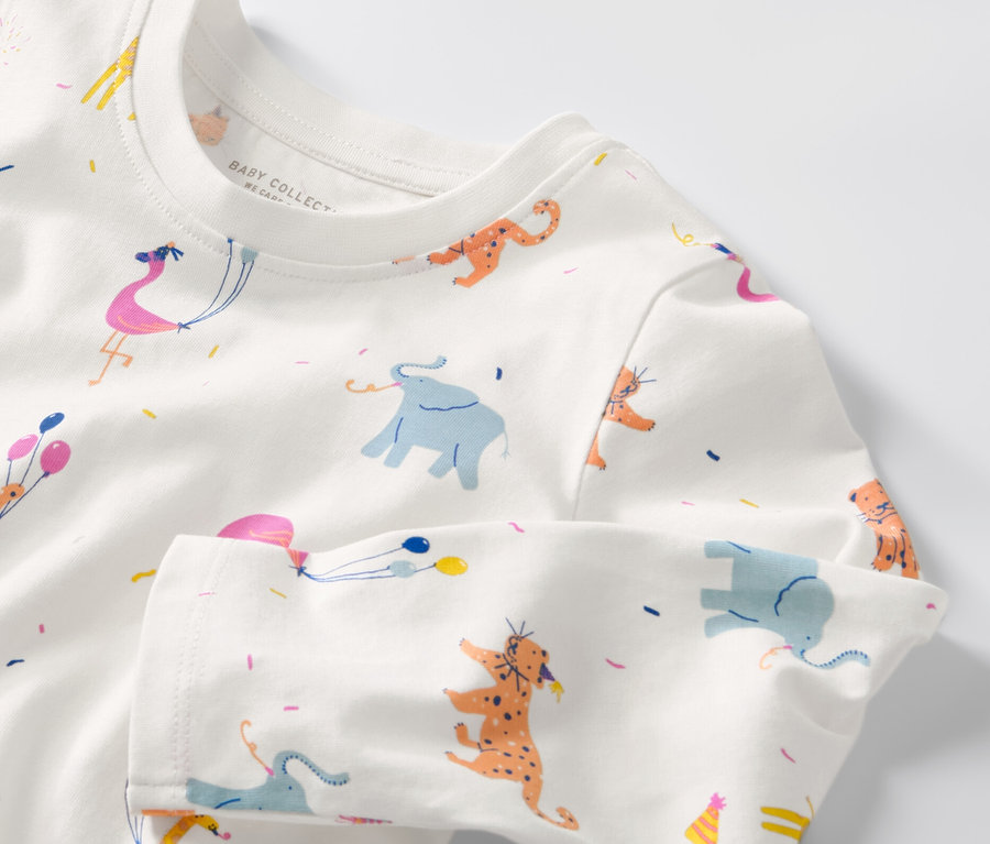 Gros plan sur un haut à manches longues pour bébé avec des motifs d'éléphants, de girafes, de tigres et de flamants roses avec des ballons.