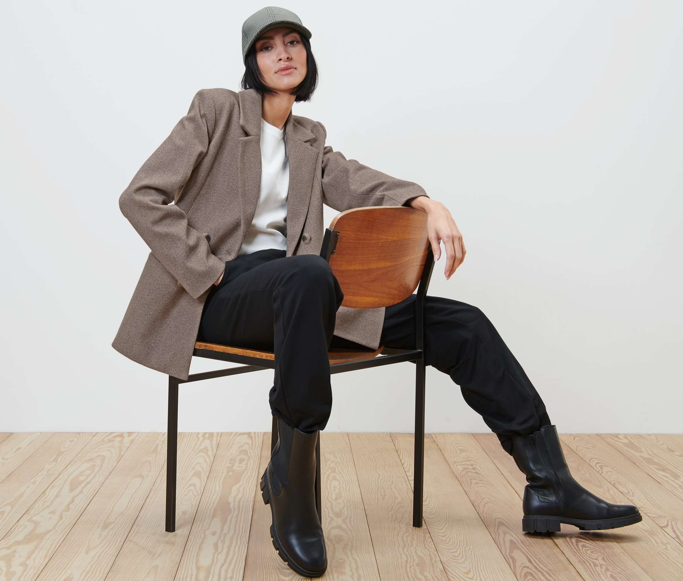 Femme assise sur une chaise portant un blazer, un pantalon et des bottes.