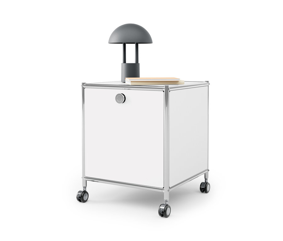 Table d'appoint blanche avec tiroir en métal « CN3 » avec une lampe grise et un livre dessus.