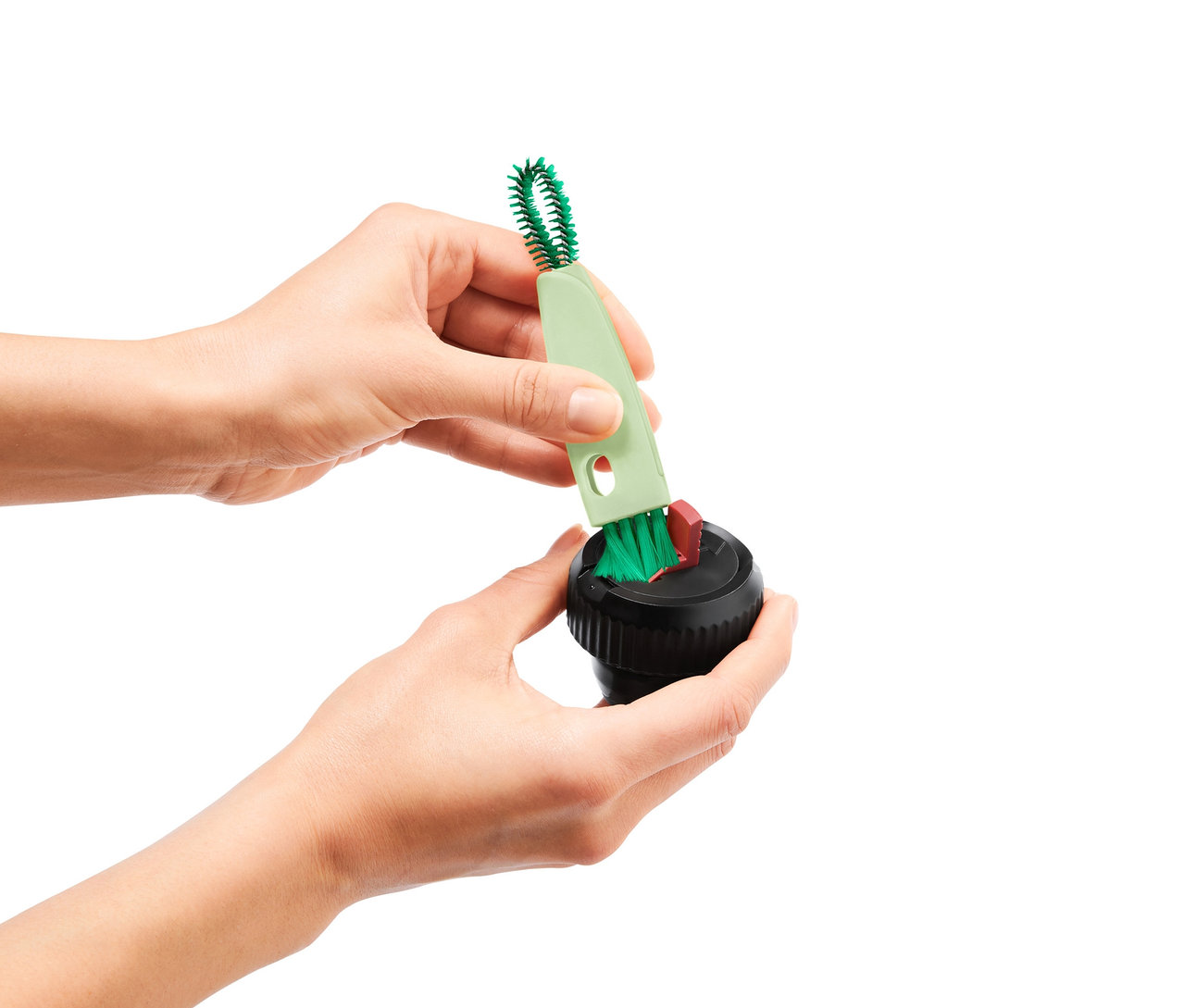 Des mains nettoient un récipient noir avec une brosse multifonction 3 en 1.