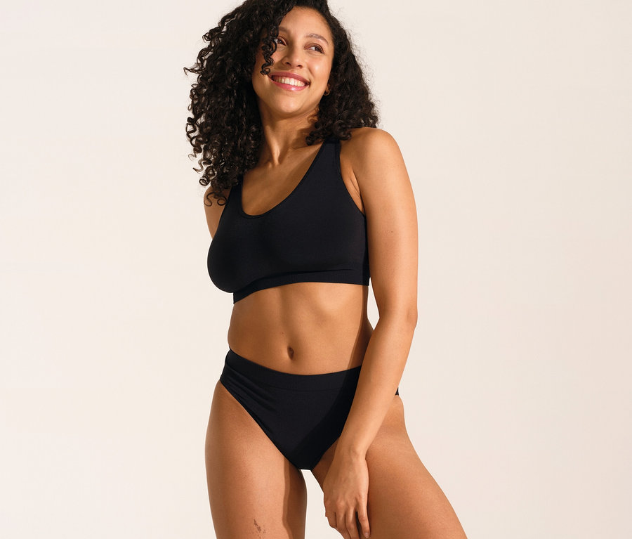 Femme souriante posant en soutien-gorge doux SCHIESSER avec coussinets noir et slip SCHIESSER Rio noir.