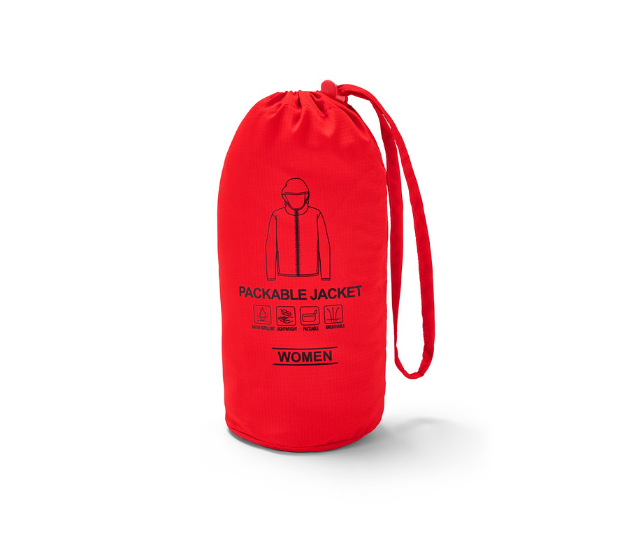 Une veste fonctionnelle légère rouge orange « pack me » dans un sac fermé.