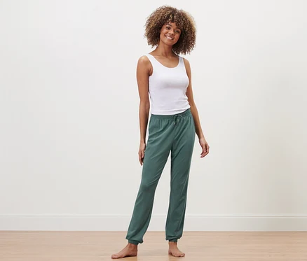 Femme posant en débardeur blanc et pantalon de pyjama.