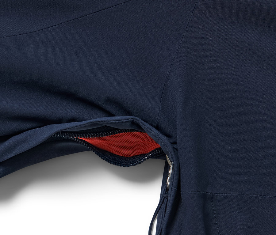 Gros plan sur une veste de ski high-tech bleue avec une poche ouverte révélant un filet rouge.