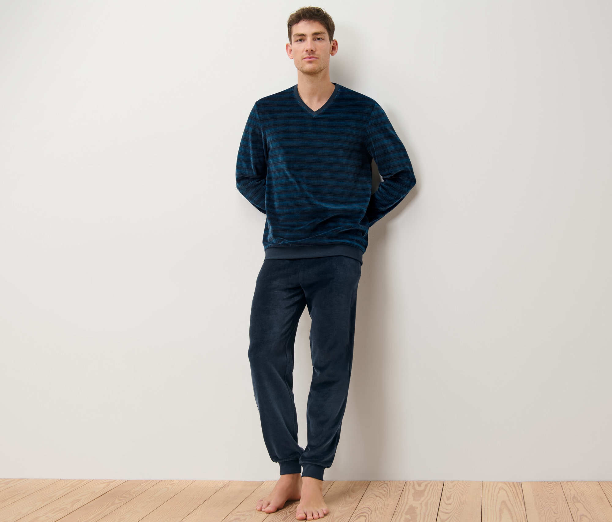 Un homme debout portant un pyjama en velours ras rayé.