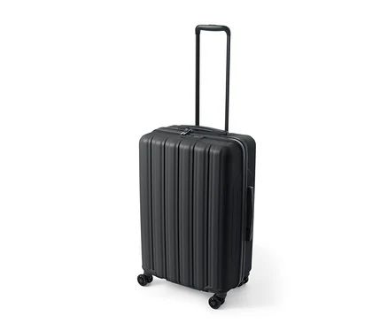 Une valise rigide noire de taille moyenne est posée sur un fond blanc.